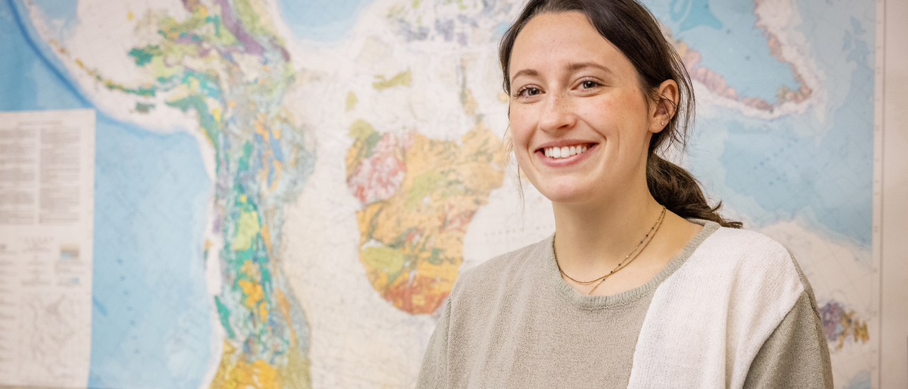 portrait of Sadie Richter EES student in front of map of Alaska
