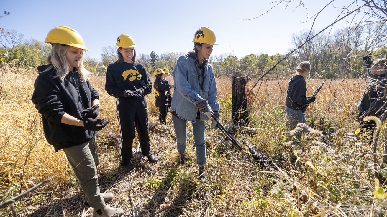 Iowa students in a prairie doing field work at Lake MacBride Nature Center